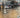 shop window with opening times painted on; faint view of inside shop, with bike parts and bikes; reflections of traffic in hornsey road